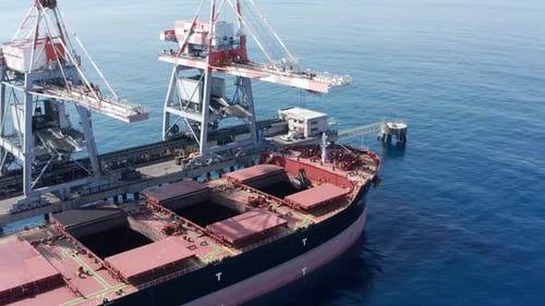 Coal carrier Cargo Ship docked at a commercial pier during unloading operation, Aerial view