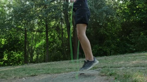 A man actively trains with a jump rope in a green park, boosting energy and strengthening his health