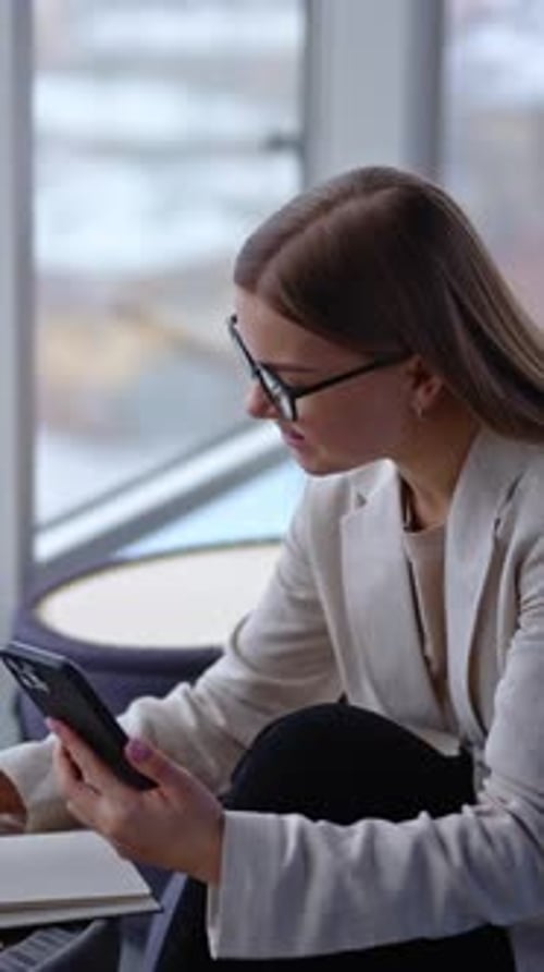Female holding a phone in front of her and speaking to someone.