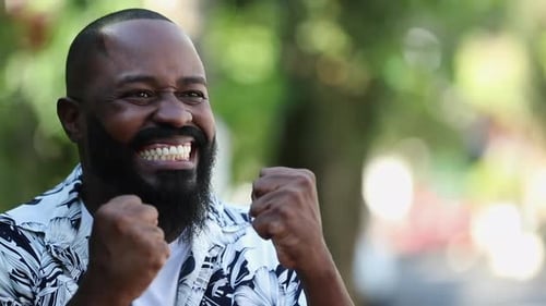 Excited Man Clenches Fists in Celebration Outdoors