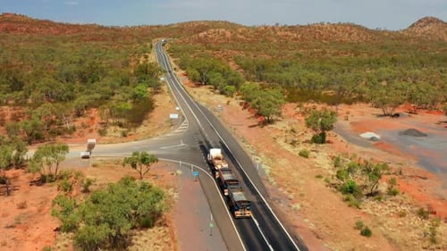 Tren de carretera de tres remolques conduciendo por la autopista en el interior de Queensland, Australia. Seguimiento aéreo s