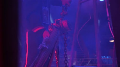 Technician Adjusting Chain Mechanism Under Blue and Red Lights