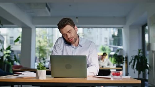 Man Talking on Phone Working at Desk
