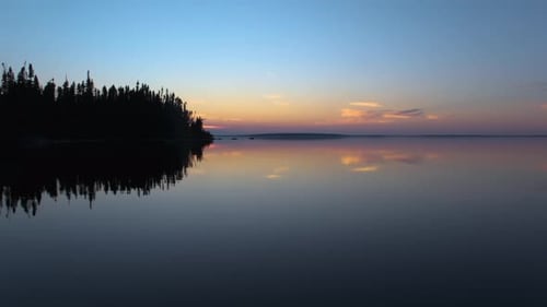 Boat riding on a perfectly calm lake on a late summer evening