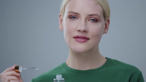 Beautiful Smiling Young Woman with Blonde Hair and Nude Makeup Having Fake Tears on Cheeks Holding a