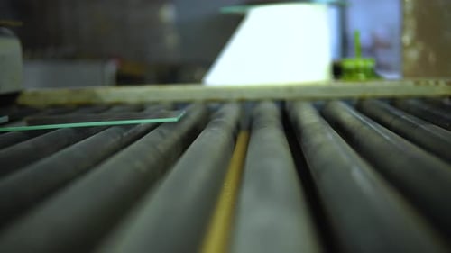 Low Angle View Of Panes Of Small Glass On Rolling Machine. Close Up