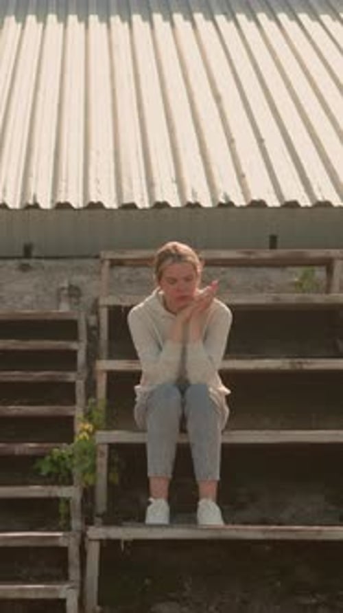 Pensive Woman Reflecting on Rustic Stadium Bleachers in Warm Sunlight