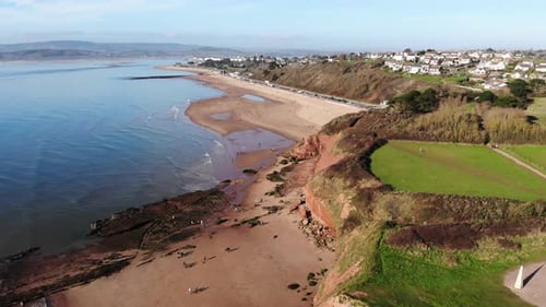 Orcombe Beach And Cliff Coastline In Exmouth With Visitors On Beach On Sunny Day. Aerial Dolly Left