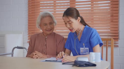 Asian young caregiver nurse examine senior woman patient at home.