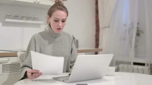 Woman Working on Laptop with Documents at Home