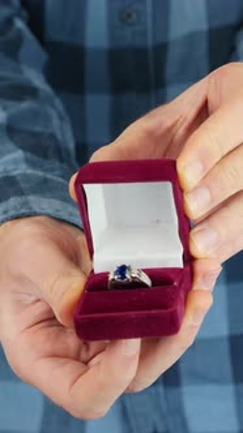 Mann hält und öffnet rote Schachtel mit Ehering. Valentinstag. Vertikales Video