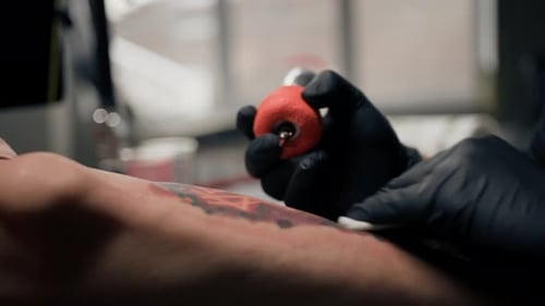Nahaufnahme - der Vorgang des Tätowierens einer Frau auf ihr Bein. Männlicher Tätowierer macht ein Tattoo