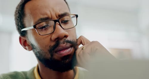 Hombre negro confuso, pensante y en la oficina con un portátil trabajando en el desarrollo de un sitio web