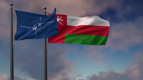 NATO and Oman Flags Waving on Flagpoles Against Cloudy Sky