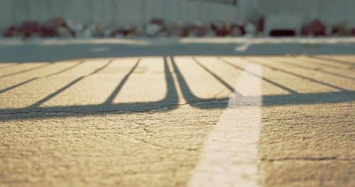 Sunlight Casting Shadows on Pavement in an Empty Parking Lot During Sunset