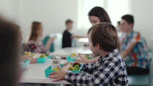 Un niño está en una cafetería con una bandeja de almuerzo llena de comida y bocadillos para su comida