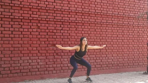 Stock Video of sporty girl performing balance and stability with squat exercise.