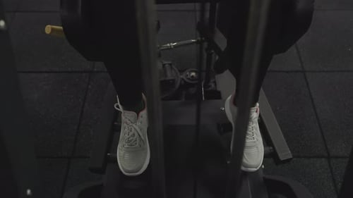 Front view of a woman's legs as she performs leg abductions on a specialized leg machine.