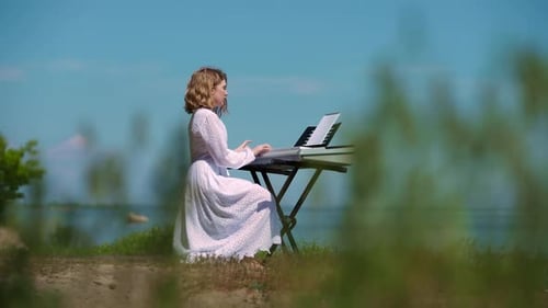 Side View Portrait of Beautiful Caucasian Teen Musician in Dress Playing Piano Synthesizer Singing