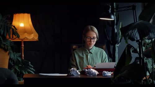woman in a green shirt sits at a table in her cozy home, typing a novel on a vintage typewriter