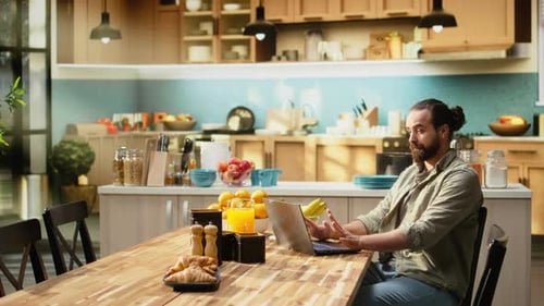 Man Working on Laptop at Kitchen Table