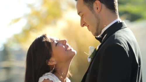 Happy Couple Embrace and Kiss Outdoors in Sunlight