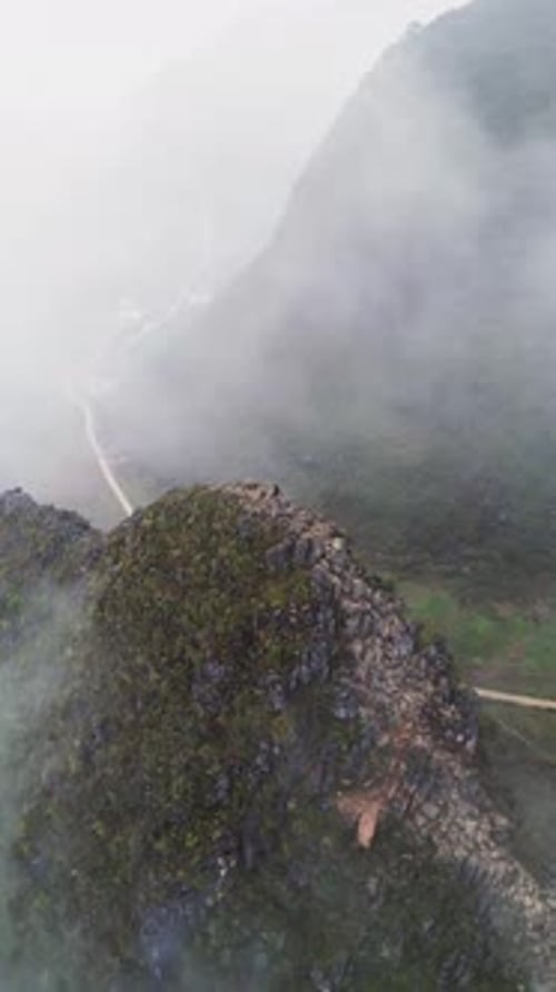 Images aériennes verticales d'un randonneur de montagne sur une crête recouverte de brouillard au-dessus d'une vallée isolée au Vietnam