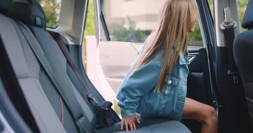 Linda garota de 10 a 12 anos se senta no banco de trás e aperta o cinto de segurança em um carro moderno.