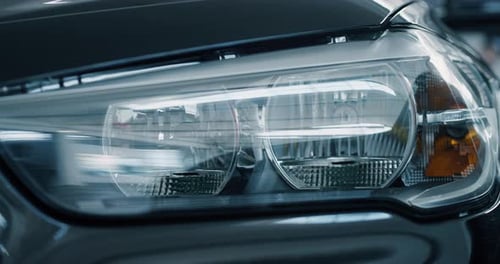 Close up of details of switched on headlights of anonymous prestigious luxury modern car. Shot in