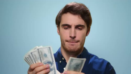 Happy Man Counting Money Cash on Blue Background. Close Up Satisfied Guy