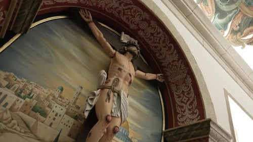 statue of jesus on the cross in a church, set against a painted backdrop depicting jerusalem with or
