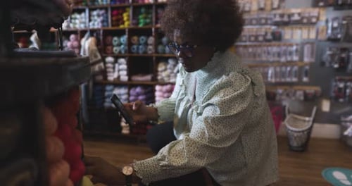 Female Shopper with Smart Phone Shopping for Yarn in Yarn Store 5054 Years