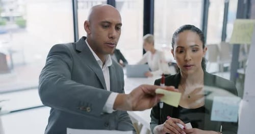 4k video footage of two businesspeople brainstorming with notes a glass wall in an office