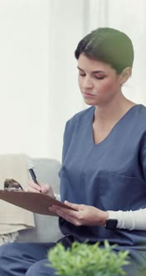 Woman Writing on Clipboard in Home Setting