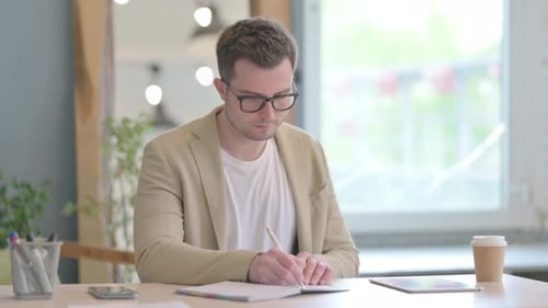 Young Businessman Writing at Work, Paperwork