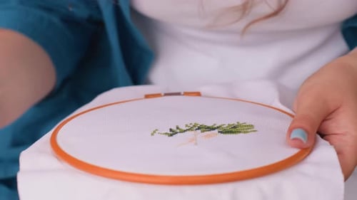 Close Up Of Woman With Blue Nails Embroidering Fabric In Hoop Outdoors