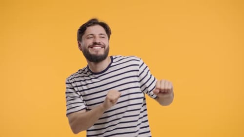 Cheerful Young Man Dancing Against Yellow Background