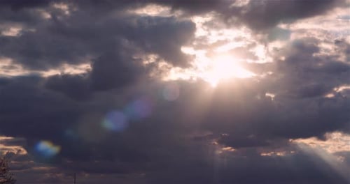 Sunlight Breaking Through Dark Storm Clouds in a Dramatic Sky