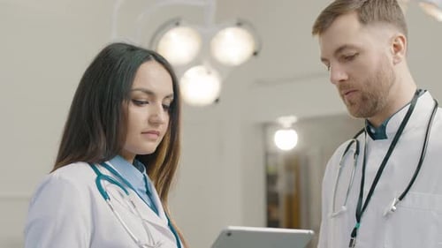 Doctors Discussing Information on Tablet in Hospital Setting
