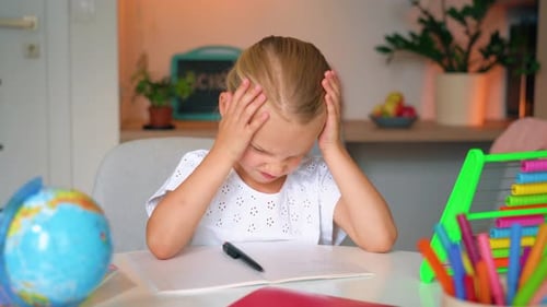Tired pupil schoolgirl writing hometask in notebook. The concept of online and home
