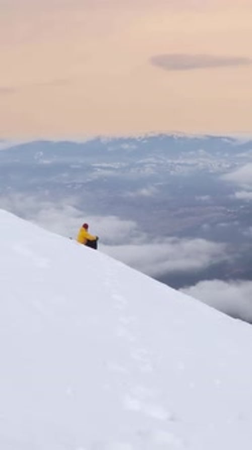 Skier Enjoys Breathtaking Views While Resting on Snowy Mountain Slope