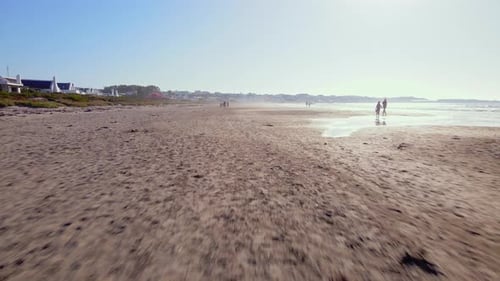 Low aerial dolly riser over Paternoster beach with strolling tourists, Weskus