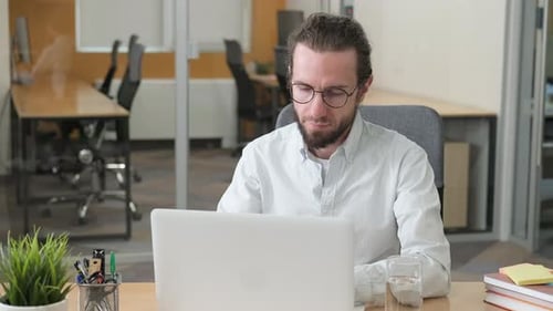 Young Adult Working Diligently on Laptop at Desk