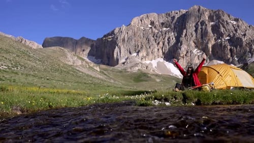 Woman Camping Near Stream in Mountain Landscape