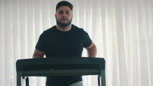 Jovem barbudo correndo na esteira em câmera lenta, vista frontal