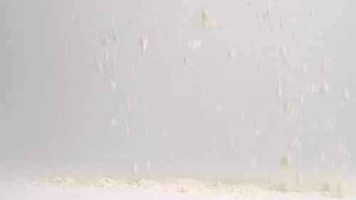 White flour falling onto white studio backdrop surface and piling up in 4k slow motion