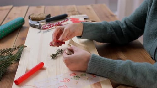 Winter Holidays And Hobby Concept - Hands With Clothespin, Paper Bag, Tag And Fir Branch Making A...
