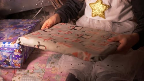 little girl putting self wrapped Christmas gift or birthday present by side. Close Up of Child hands