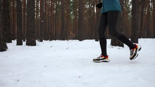 Legs Jogging Through Snow Covered Forest in Winter