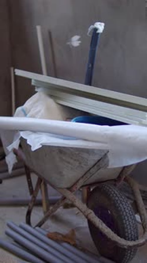 Loaded Wheelbarrow with Pipes and Panels in Construction Room